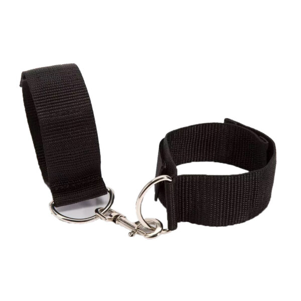 "Adjustable black ankle restraints with a metal connector clip, worn around ankles, paired with black high heels."