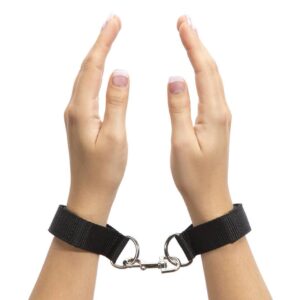 "Adjustable black wrist restraints with a metal connector clip, shown on hands with manicured nails."