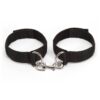 "Adjustable black wrist restraints with a metal connector clip, shown on hands with manicured nails."