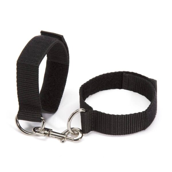 "Adjustable black wrist restraints with a metal connector clip, shown on hands with manicured nails."