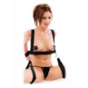 A person wearing a black bondage harness with attached wrist restraints, shown from the back.